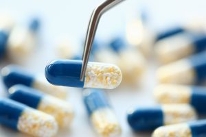 A pill capsule being picked up by tweezers